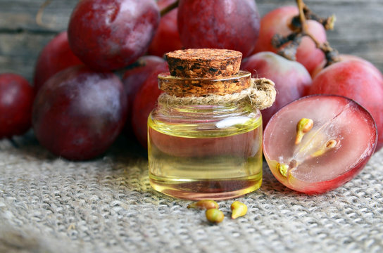 Bottle of organic grape seed oil for spa and bodycare and fresh ripe grapes berries on old wooden table.Healthy food,Bio,Eco products concept.Selective focus.