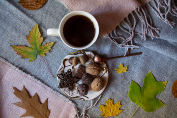 A cup of tea and sweet snacks with decoration by autumn leaves on the warm plaid. Seasonal still life.