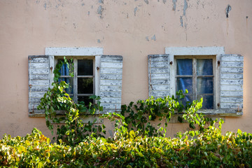 Fototapeta na wymiar White window shutters on old wall of Mediterranean city.
