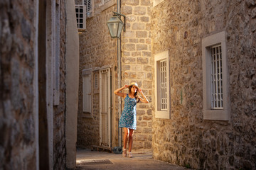Fototapeta na wymiar Europe summer travel mediterranean destination. Tourist woman on vacation, walking on the streets of old and beautiful Mediterranean city in hat and summer dress