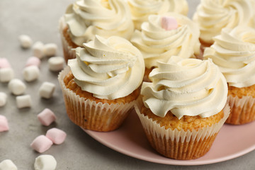 Plate with sweet cupcakes and marshmallows on grey table, closeup