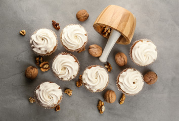Delicious cupcakes with walnuts on grey table