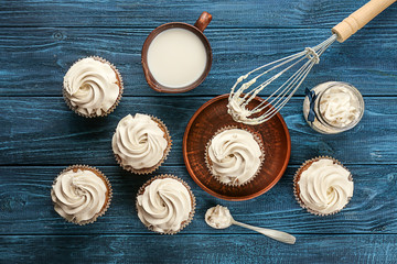 Fototapeta na wymiar Tasty cupcakes with cup of milk on wooden table