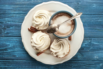 Tasty cupcakes with cup of coffee on wooden table