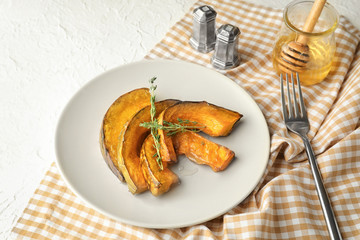 Plate with tasty baked pumpkin pieces and honey on white table