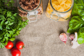 Pasta with garlic, cherry tomato and basil before cooking on linen in the kitchen - copy space