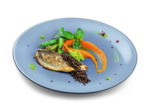 Plate with delicious grilled seabass fish fillet steak and vegetables isolated on white background. Healthy gourmet food.