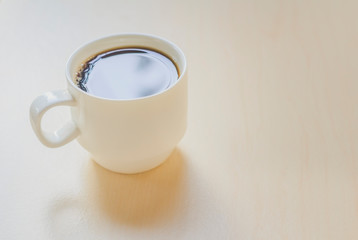 White cup with coffee. Light background.