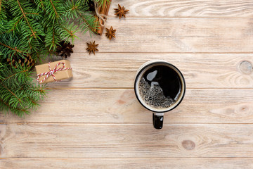 Christmas background with hot coffee, gift box, fir branches and cones on wooden table, top view copy space. Christmas holidays background, flat lay
