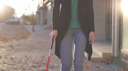 Portrait young woman visually impaired with glasses and a cane in the city ,slow mo