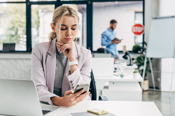 beautiful young businesswoman using smartphone at workplace