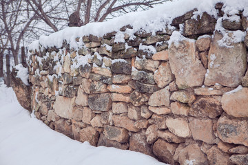 stone fence covered by snow