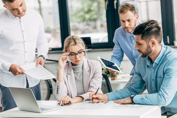 young businesswoman in eyeglasses working with male colleagues in office