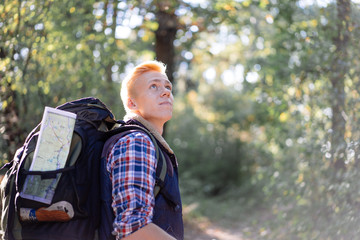 Young man enjoying hiking alone with nordic walking sticks in the forest