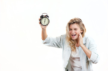 Very beautiful girl tired with a headache from the fact that the alarm clock is ringing and it's time to get up on a white isolated background