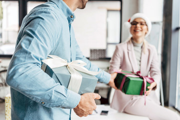 Obraz premium cropped shot of young businessman presenting christmas gift to female colleague in office