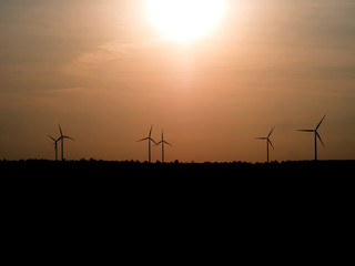 silhouette wind turbine in grass field with twilight
