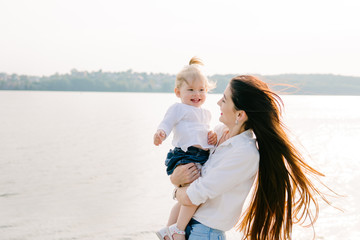  beautiful woman in the park or forest near the trees and holding her smiling little baby girl 