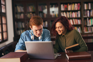 Two students read and learns by the book shelf at the city library.Reading a book.