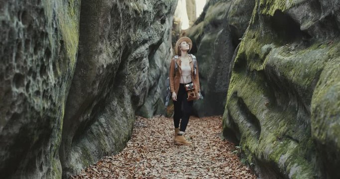 Back view of young traveler girl walking at rocks, woman tourist walking rocks