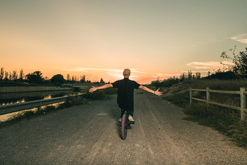 Portrait of a young man with a bmx bicycle. Guy riding a bike in a sunset