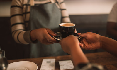 Fototapeta na wymiar Closeup of an African barista giving a customer her cappuccino