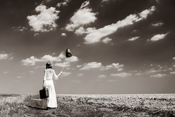 photo of the beautiful young woman with heart-shaped balloon and suitcase in the field