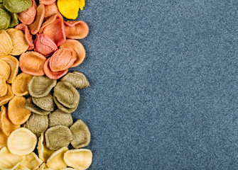 Traditional Italian Rainbow pasta. Colored raw pasta on a stone background