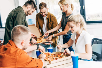 close-up shot of colleagues having pizza for lunch at office