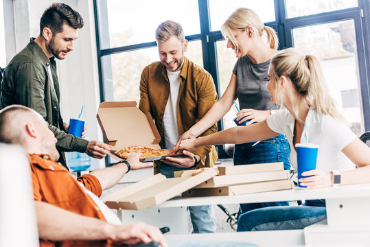 successful happy entrepreneurs having pizza for lunch together while working on startup at office