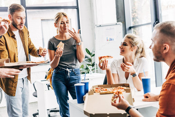 group of successful entrepreneurs having pizza for lunch together while working on startup at office