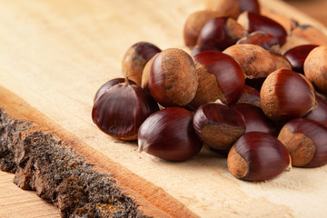 Chestnuts on wooden board and autumn leaves