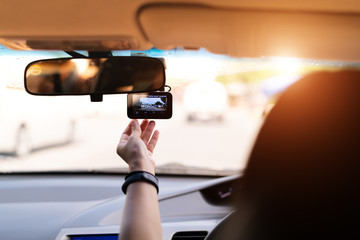 Front camera car recorder, woman set video recorder next to a rear view mirror - Powered by Adobe
