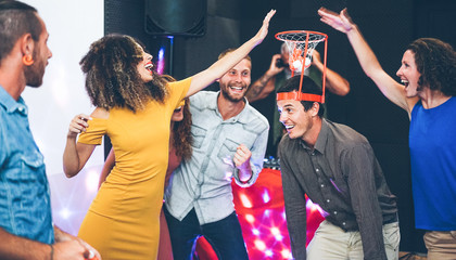 Group of happy people playing funny basketball game inside pub cocktail bar