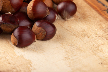 Chestnuts on wooden board and autumn leaves
