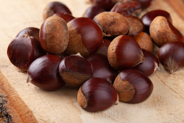 Chestnuts on wooden board and autumn leaves