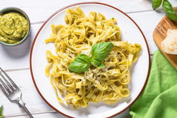Tagliatelle pasta with pesto sauce and parmesan on white.