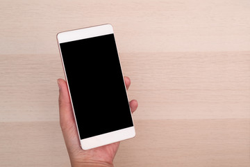 hand holding smartphone with blank screen isolated on wooden background