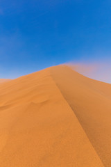 Fototapeta na wymiar Sand blowing over Big Daddy Dune, Sossusvlei, Namib-Naukluft National Park, Namibia.