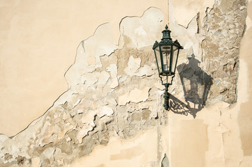 an ancient dark green squiggly lantern casting a cloud over a grungy house wall in Prag - Czech Republic - 229551641