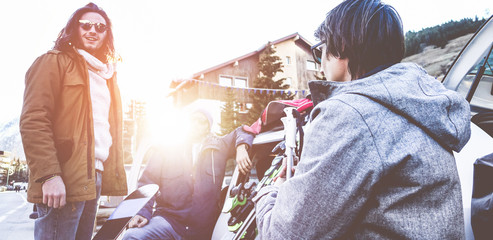 Obraz premium Happy friends arrived at winter vacation village with skies and snowboards