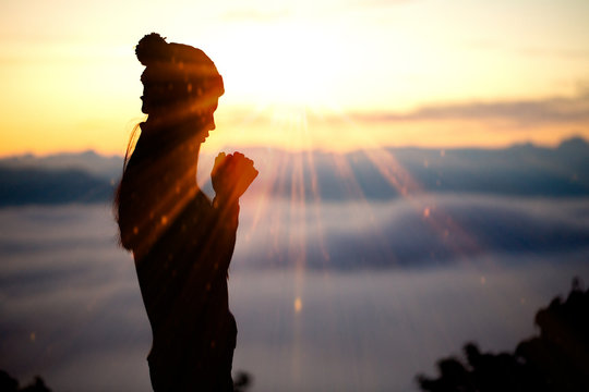 Silhouette Of Woman Praying With Cross Over Beautiful Sky Background