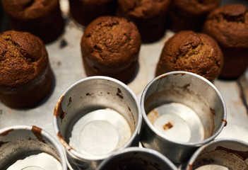 Freshly baked muffins sitting with tins on a bakery counter