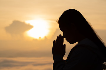 Silhouette hand girl praying at sunset