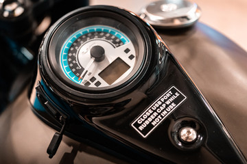 Speed instruments and display on vintage customized motor bike. Design details, black metal casing. Digital and analog device.