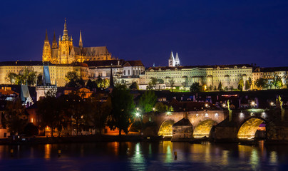 illuminated beautiful Prague at twilight hour with a cloudless blue sky reflecting in the Vltava river - view at the castle and the Karlsbrücke - Karlův most Czech Republic © Alexandra Giese