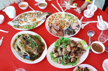 Steamed snapper fish with lemon, Braised duck with Dim sum and Deep Fried Crab Meat Rolls or Hoi Jo, Chinese food on plate on red table
