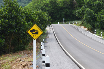 Traffic road sign warning up to hill steep climb (8%) , Paved road in the forest filled with trees on mountain in Thailand

