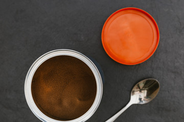 Instant coffee in tin jar spoon on dark background