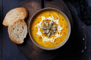 Vegetarian pumpkin cream soup. Autumnal pumpkin soup. Home made pumpkin cream soup decorated with cream, seeds, bread